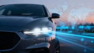 Современный автомобиль с ярко горящими светодиодными фарами Wholesale, на фоне которого изображена глобальная, управляемая данными стратегия цепочки поставок.